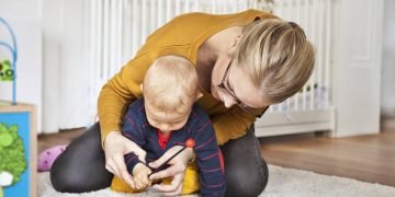 New mom holding her baby, reflecting on expert parenting tips for the first year.